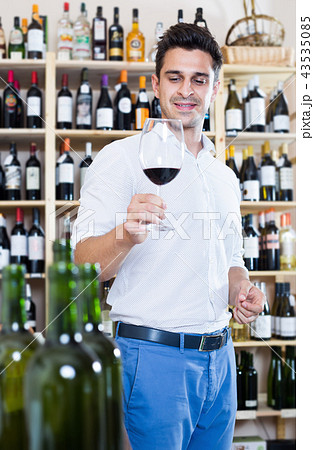 Man customer holding glass of red wine in winery section 43535085
