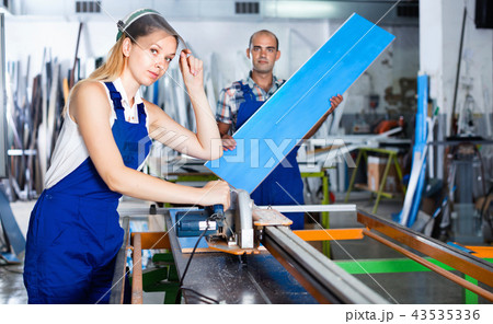 Female worker in protective face shield, standing near circular saw 43535336