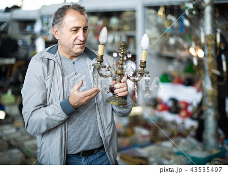 Adult male is choosing lamp at the market of old things. Adult male is choosing lamp at the market of old things. 43535497
