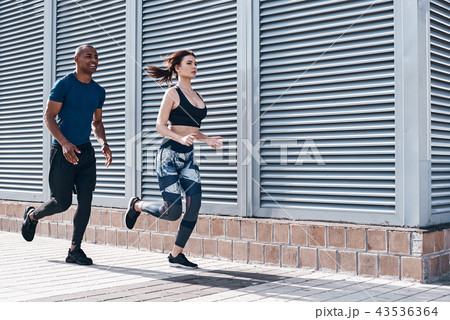 Urban sports. Full length of young couple in sport clothing running through the city street together 43536364