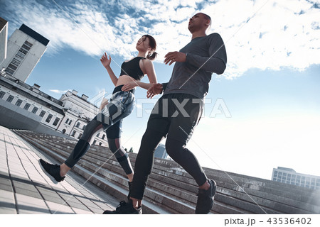 Urban sports. Full length of young couple in sport clothing running through the city street together 43536402