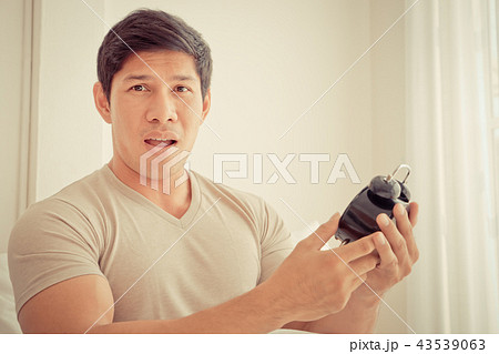 Casual man is surprise on late alarm clock time 43539063