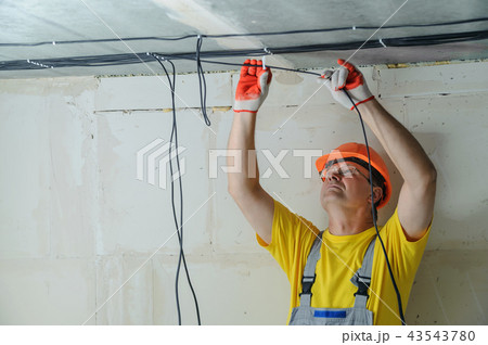 The worker is plastering the electric cables. 43543780