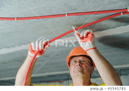 The worker is plastering the electric tubes. 43543783