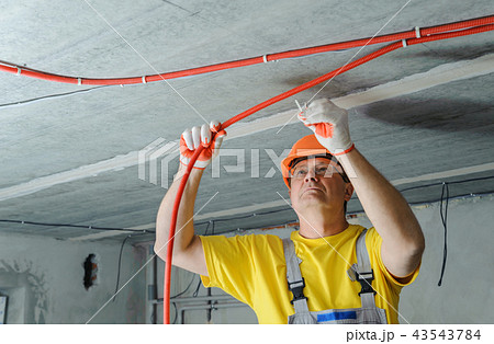 The worker is plastering the electric tubes. 43543784