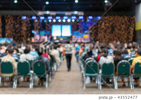 Abstract blurred photo of conference hall or seminar room in Exhibition Center with speakers on the stage and attendee background, seminar and study concept Abstract blurred photo of conference hall or seminar room in Exhibition Center with speakers on the stage and attendee background, seminar and study concept 43552477