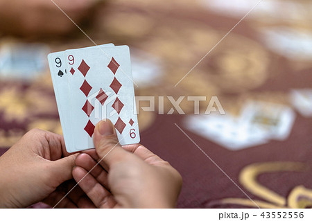 Reaw view closeup of asian woman playing card with money on the table over the carpet, risk and luck game concept 43552556