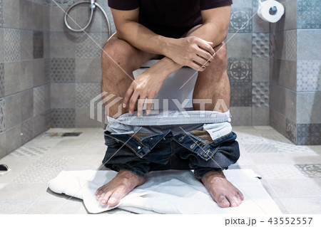 Man sitting on toilet bowl Man sitting on toilet bowl 43552557