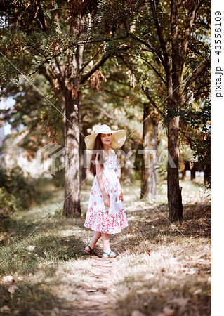 a girl with wide hat walks along a forest path a girl with wide hat walks along a forest path 43558109