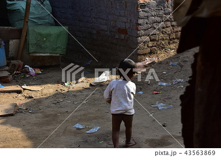 インドの首都デリー 線路沿いのスラム 家の前の道路を掃除する子供の写真素材