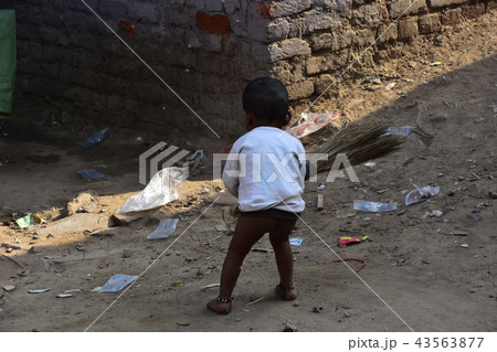 インドの首都デリー 線路沿いのスラム 家の前の道路を掃除する子供の写真素材