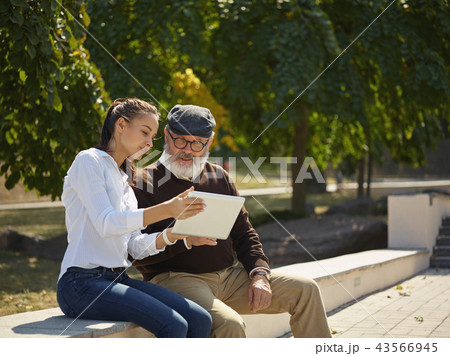 Portrait of young girl sitting with grandfather at park 43566945
