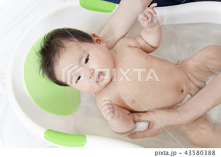新生児の入浴 沐浴方法を説明するマニュアル用写真 沐浴時の新生児の安心 安定する支え方イメージの写真素材