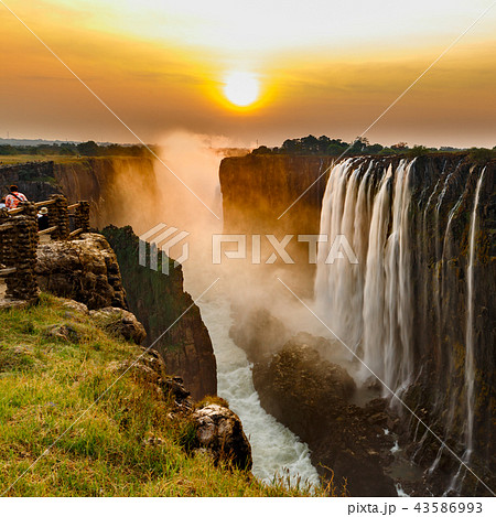 Victoria falls sunset with orange sun and tourists 43586993