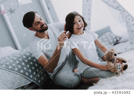 Father Combing Daughter Sitting on Bed in Bedroom 43591092