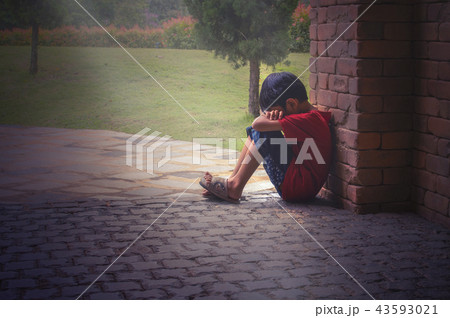 The boy sitting sadly beside the wall. 43593021