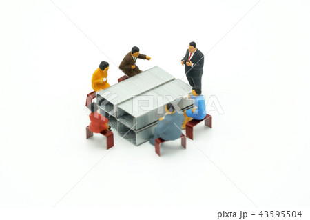 Miniature people sitting on red staples placed  43595504