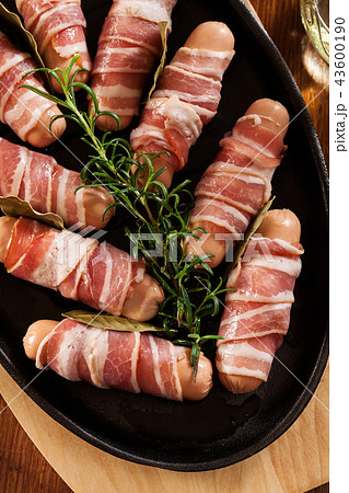 Raw mini sausages wrapped in smoked bacon Raw mini sausages wrapped in smoked bacon 43600190