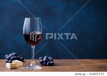 Glass of red wine with fresh grape and cheese on wooden table. Blue background. Copy space. 43605737