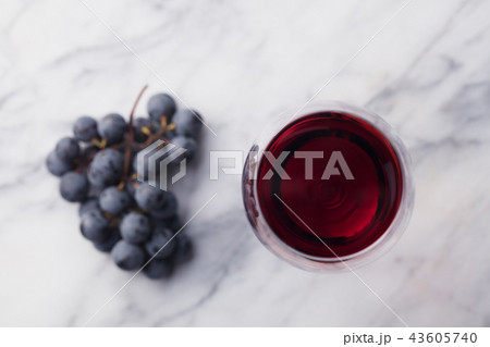 Red wine in glass with fresh grape on marble table background. Top view. 43605740