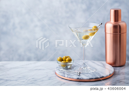 Martini cocktail with olives and bar shaker on marble table background. Copy space. 43606004