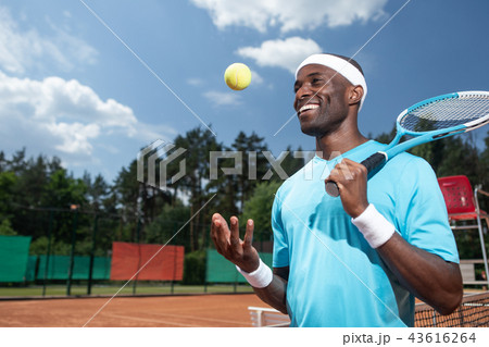 Cheerful man is using tennis equipment outside Cheerful man is using tennis equipment outside 43616264