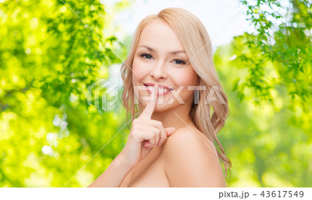 woman with finger on lips over natural background 43617549