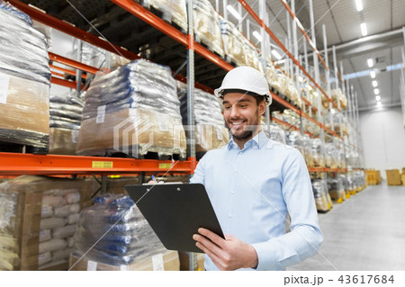 businessman in helmet with clipboard at warehouse 43617684