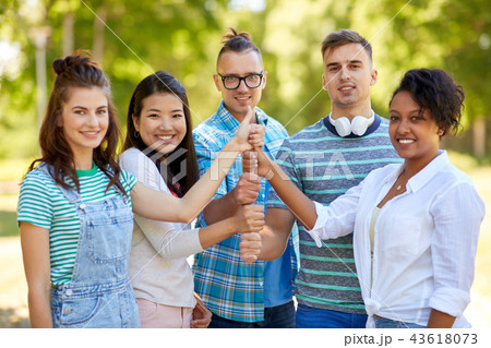 happy friends making thumbs up gesture in park 43618073