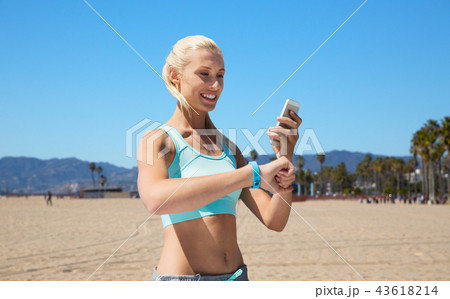 happy woman with fitness tracker and smartphone happy woman with fitness tracker and smartphone 43618214