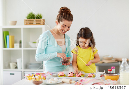 happy mother and daughter cooking cupcakes at home 43618547