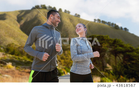 couple with earphones running over big sur couple with earphones running over big sur 43618567