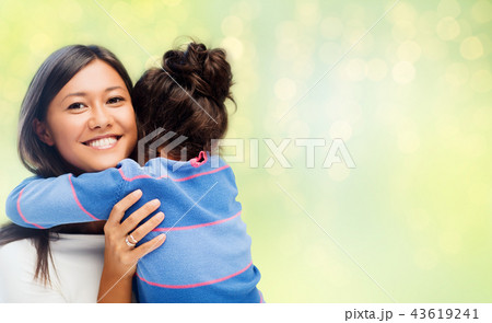 happy mother and daughter hugging over green happy mother and daughter hugging over green 43619241