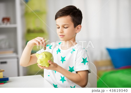 little boy putting coin into piggy bank at home little boy putting coin into piggy bank at home 43619340