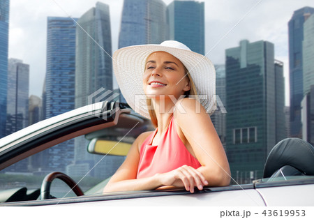woman in hat in convertible car over singapore 43619953