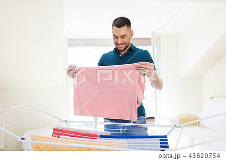 smiling man with laundry and drying rack at home smiling man with laundry and drying rack at home 43620754