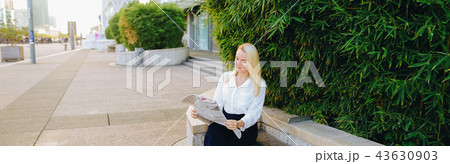 Lady reading newspaper outdoors in   with close up face. 43630903