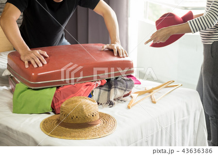 man trying to fit all clothing to packing his red suitcase befor man trying to fit all clothing to packing his red suitcase befor 43636386