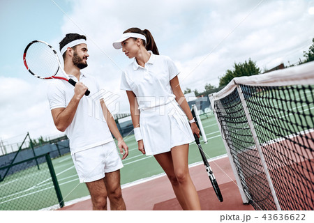 They play like a team. Beautiful young woman and man holding tennis racket and discussing set They play like a team. Beautiful young woman and man holding tennis racket and discussing set 43636622