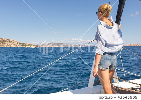 Woman relaxing on a summer sailin cruise, sitting on a luxury catamaran, standing in Maddalena Woman relaxing on a summer sailin cruise, sitting on a luxury catamaran, standing in Maddalena 43645909