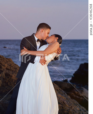 Bride and groom kissing on beach 43646268