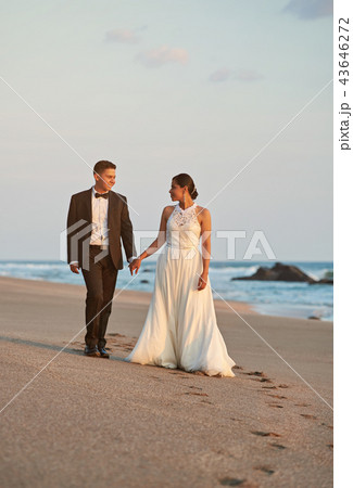 Bride and groom walking on beach Bride and groom walking on beach 43646272