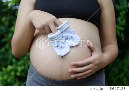 pregnant couple holding baby socks on belly 43647123