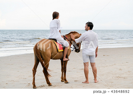 Young couple goes horse riding on tropical beach. 43648692