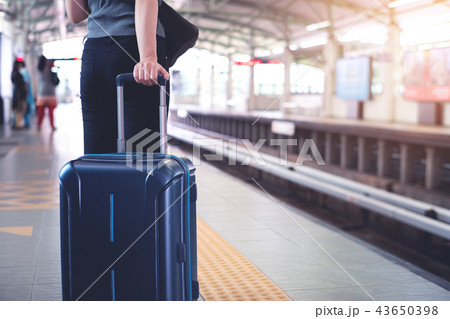Woman with suitcase waiting a train in platform 43650398