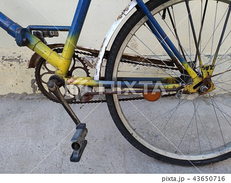 Fragment of an old bicycle painted in yellow, blue Fragment of an old bicycle painted in yellow, blue 43650716