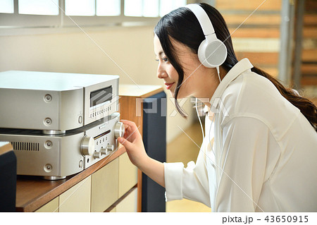 リビングルームのオーディオで音楽鑑賞する若い女性 43650915