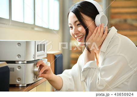 リビングルームのオーディオで音楽鑑賞する若い女性 43650924