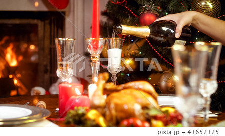 Closeup image of hand filling glasses with champagne on Christmas dining table 43652325