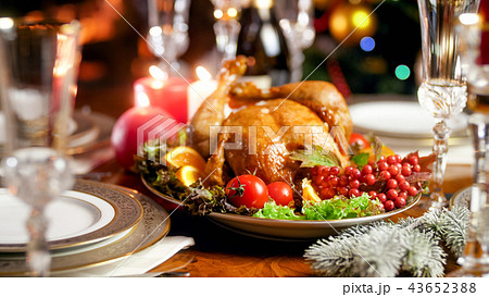 Closeup image of served family festive table against glowing Christmas tree and burning fireplace 43652388